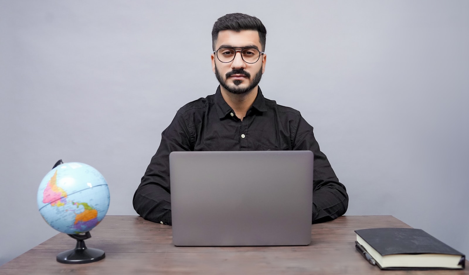 a man sitting at a desk with a laptop and a globe