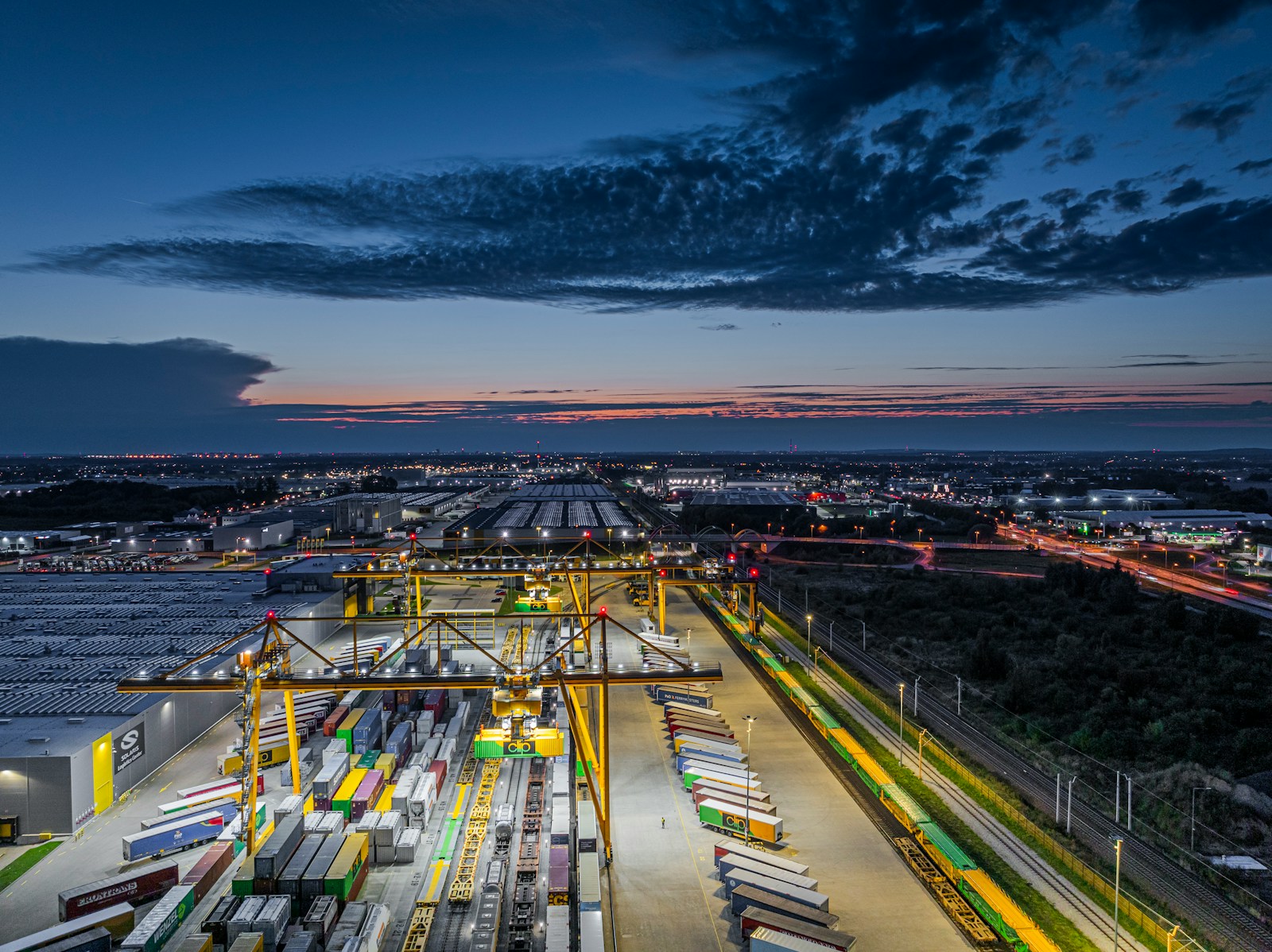 Busy shipping port with cranes and containers at dusk