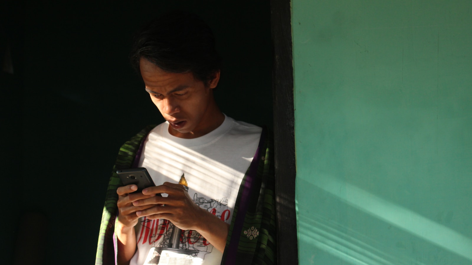 a man looking at his cell phone in a doorway