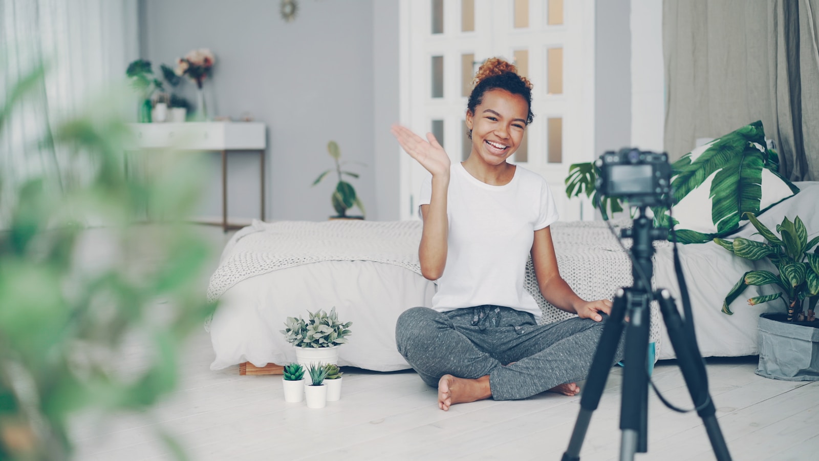 Young woman waves at camera in a room