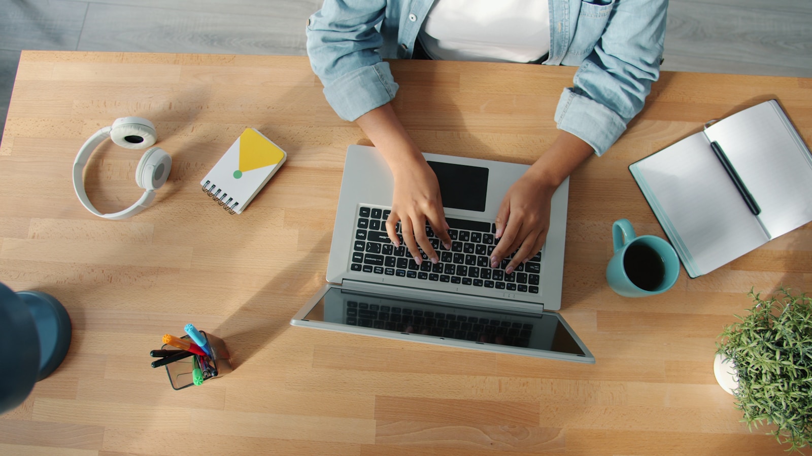 Person typing on a laptop at a wooden desk.