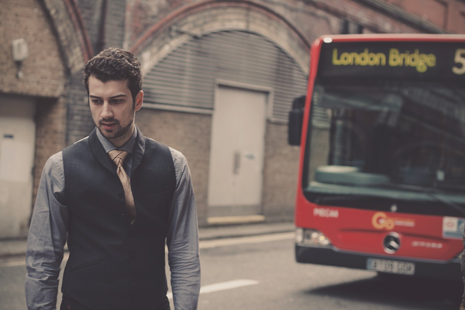A man standing in front of a bus on a city street