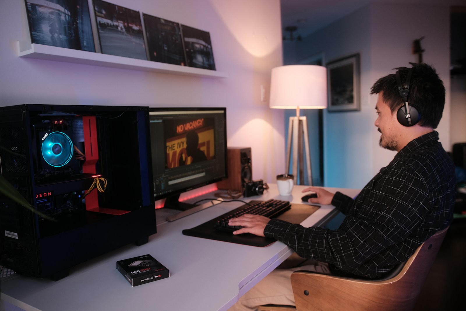 a man wearing headphones and sitting at a desk with a computer