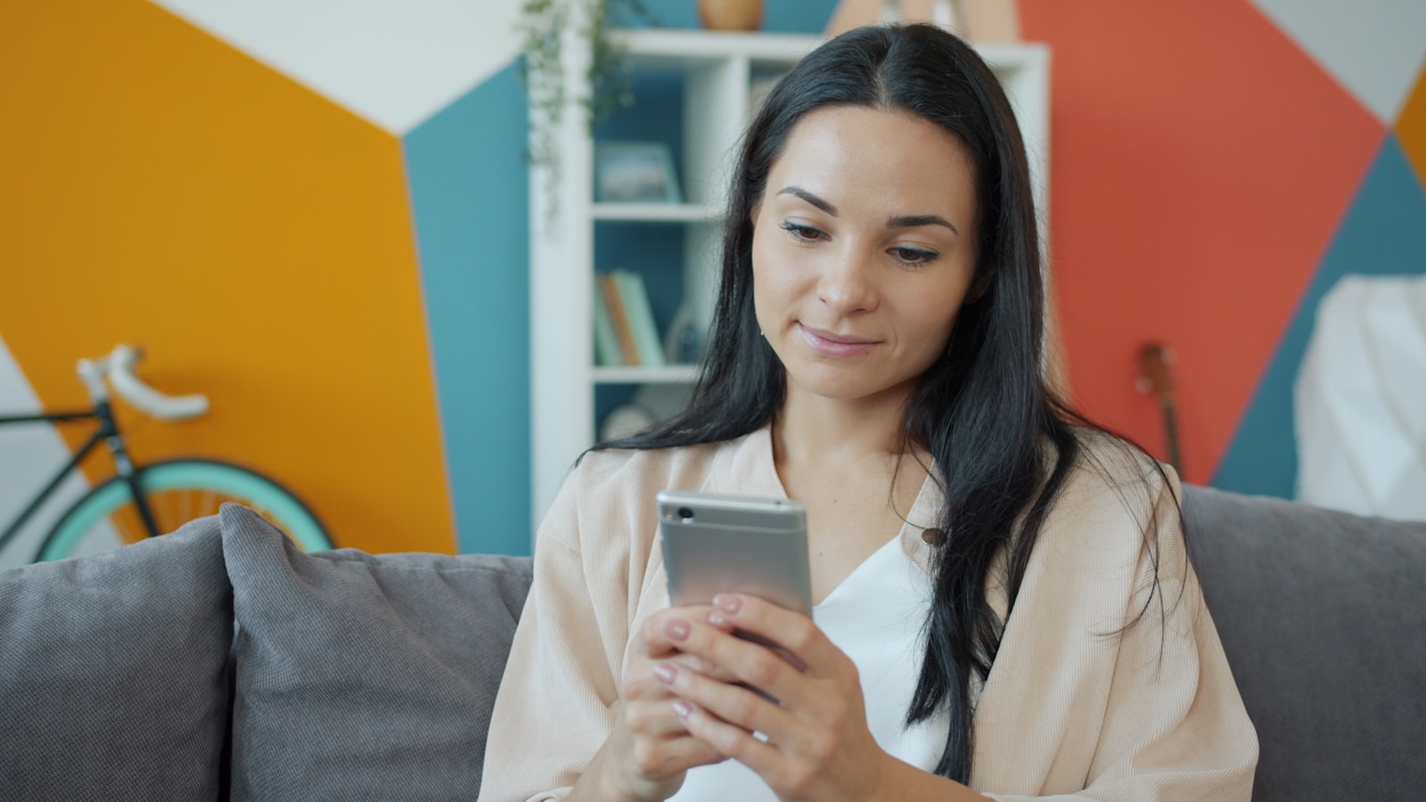 A woman looking at her smartphone on a couch.